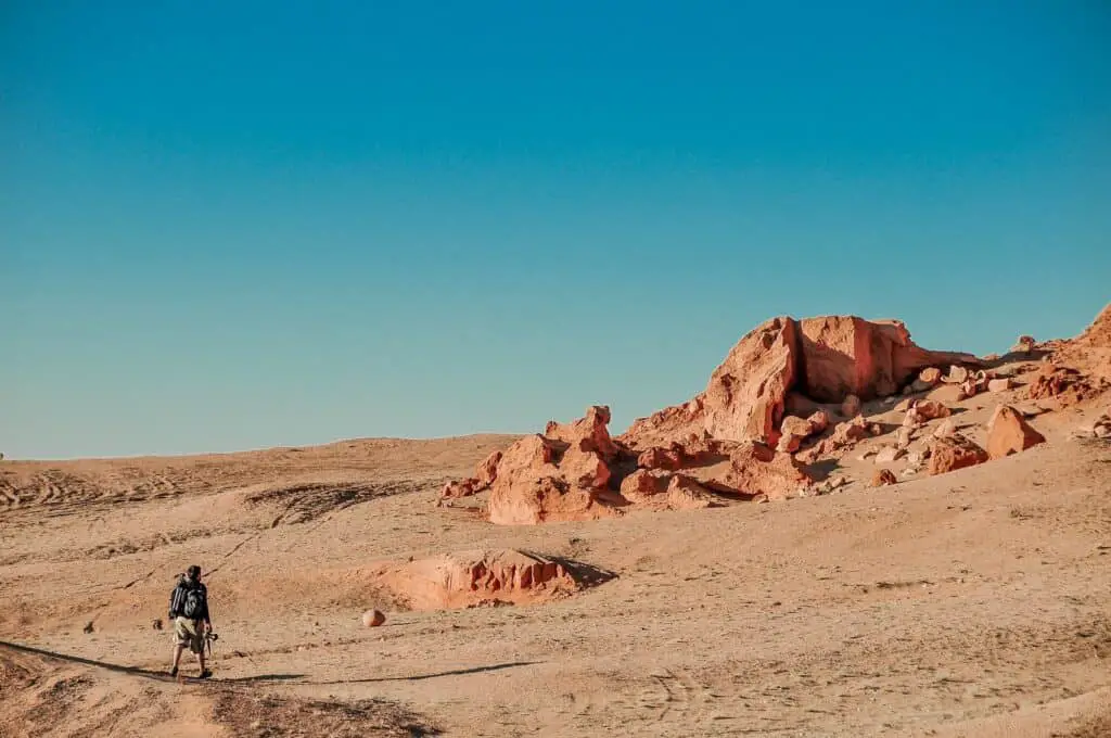 man in black jacket walking on brown sand during daytime