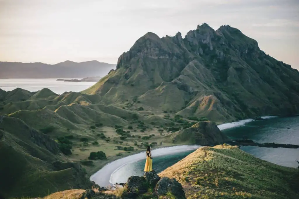 woman standing on mountain near body of water