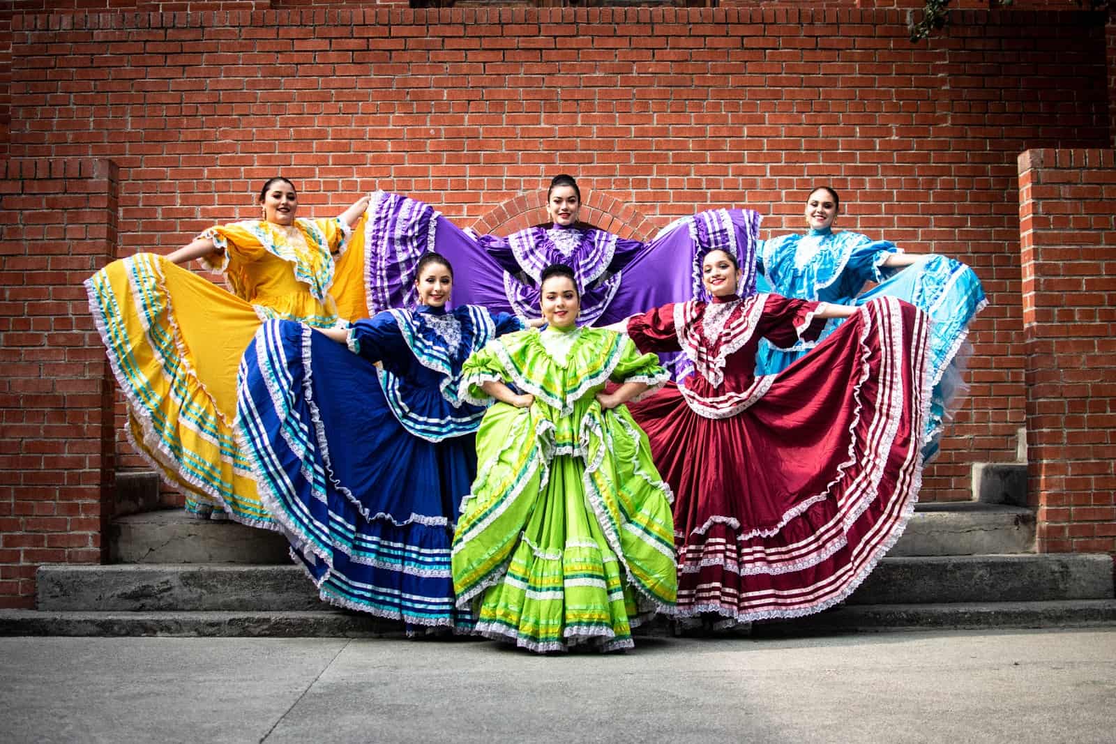 group of people in green and blue dress dancing on street