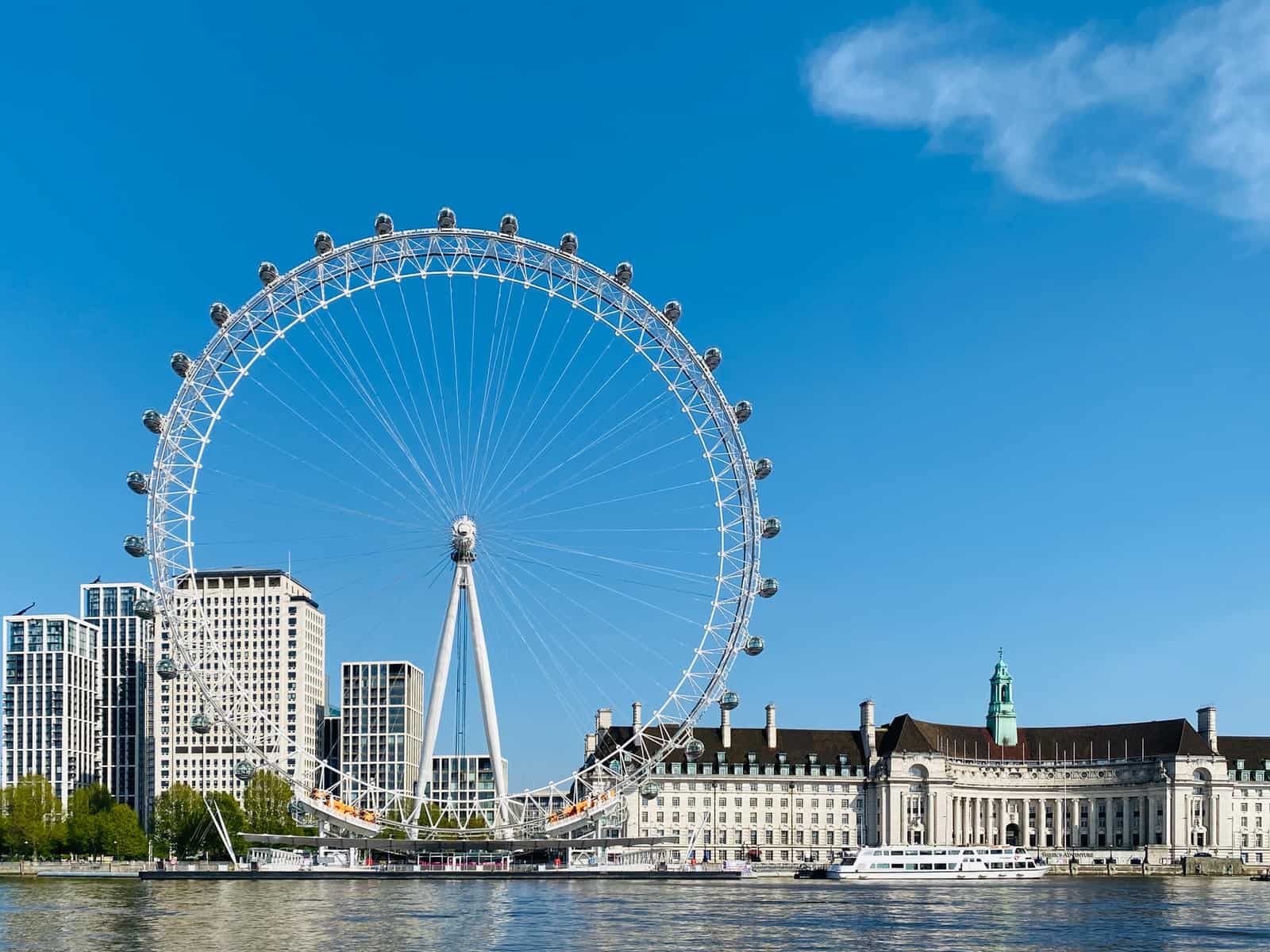 white ferris wheel near white concrete building under blue sky during daytime