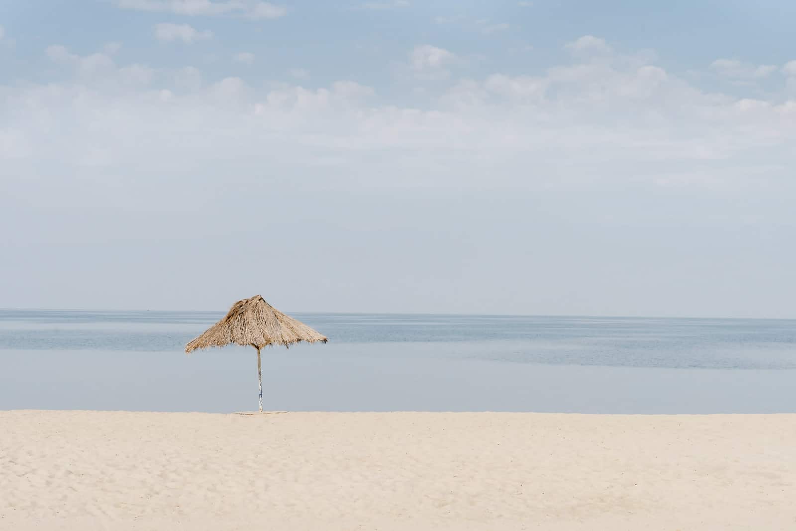 brown beach umbrella on white sand during daytime