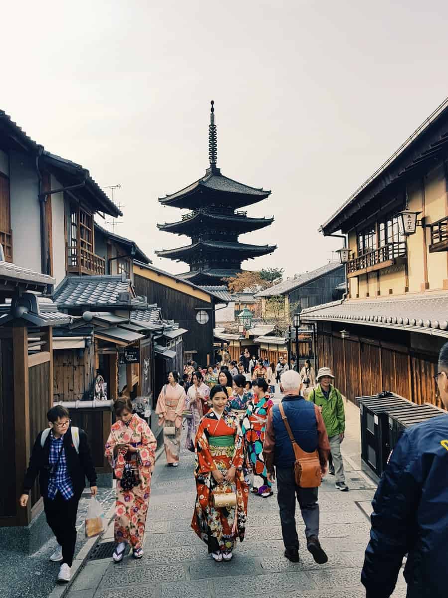 people walking along road leading to a pagoda