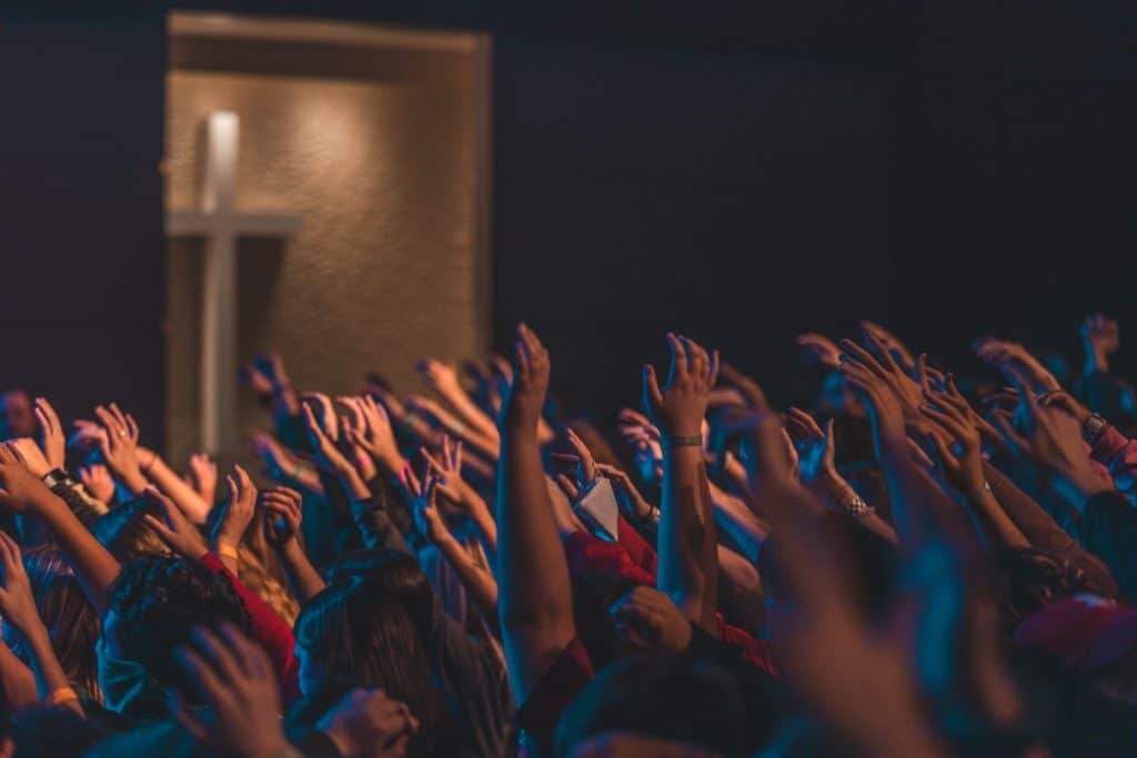 people raising their hands in front of stage