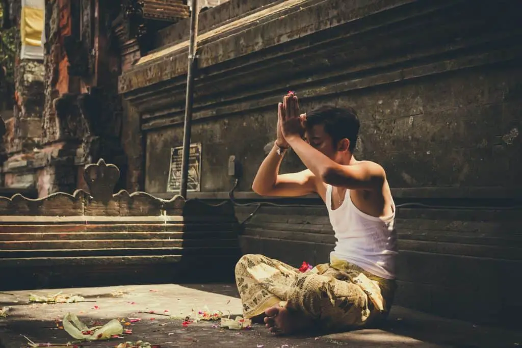 man in white tank top praying