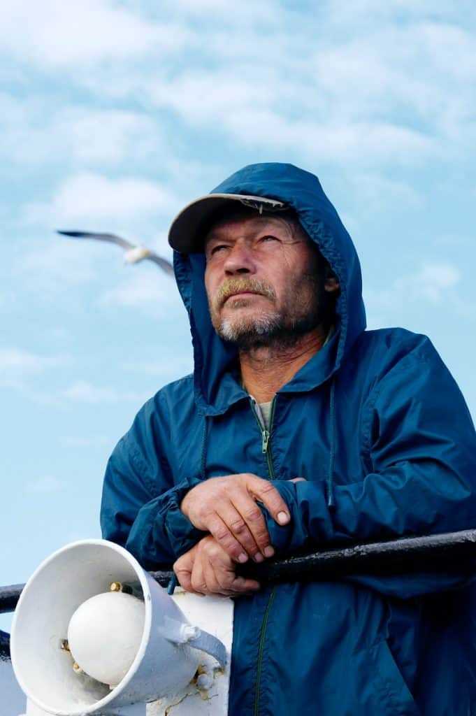 man in blue zip up hoodie holding black and white stick