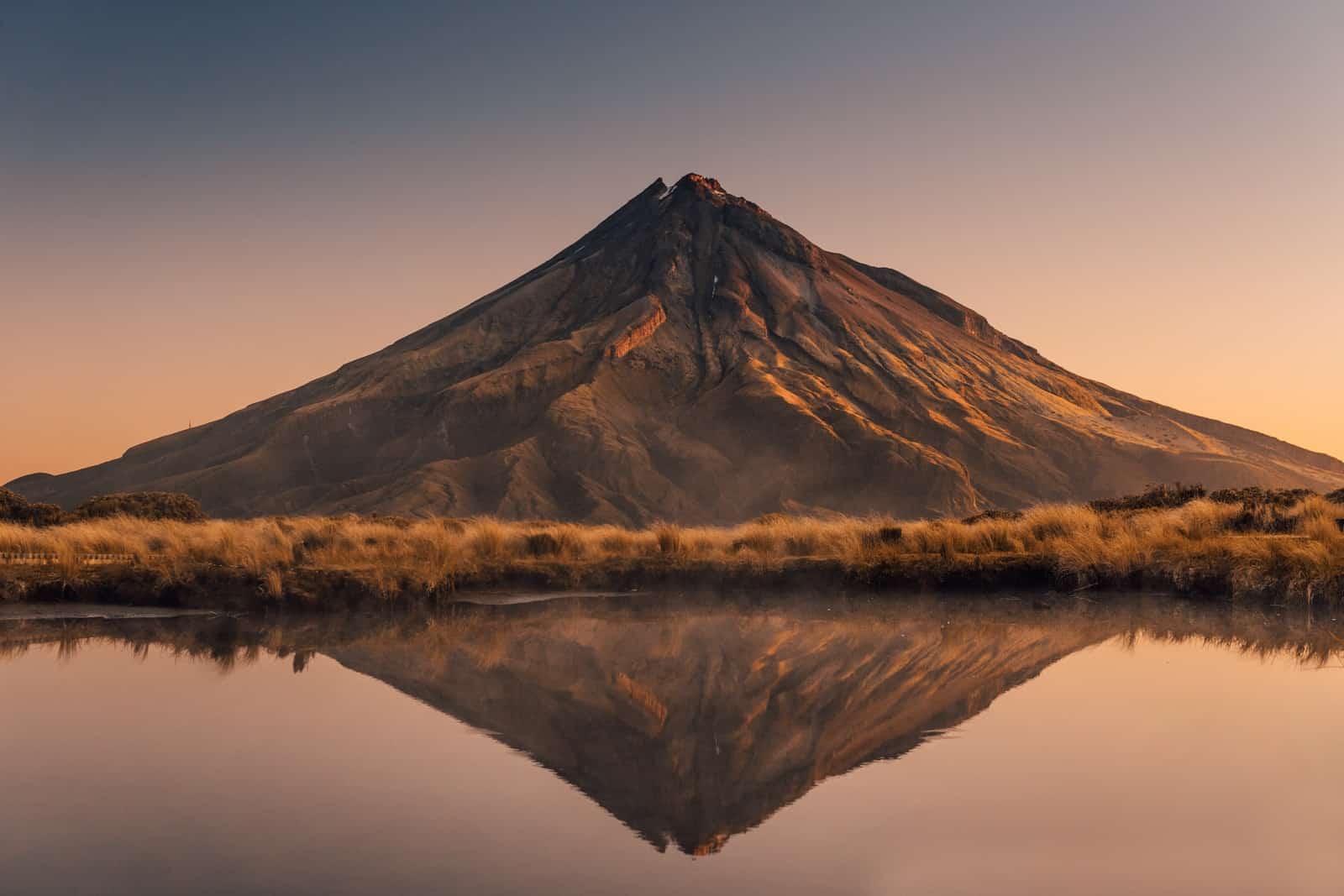 brown mountain near body of water during daytime