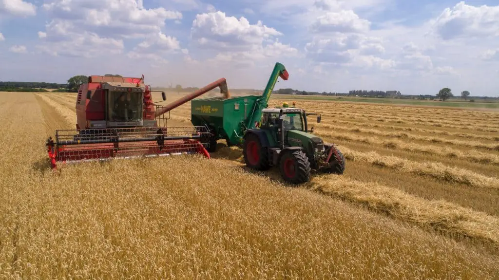 two green and red cultivators on brown field