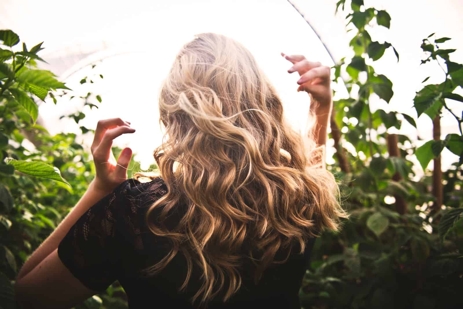 blonde haired woman in black top surrounded by tall plants